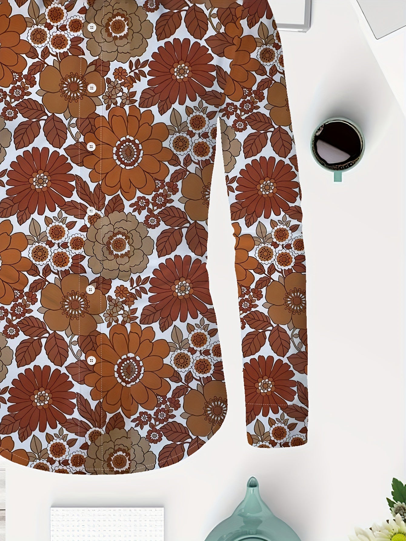 Person wearing a unisex floral button-down shirt with a lapel collar, featuring a random print in vibrant orange, white, and green.