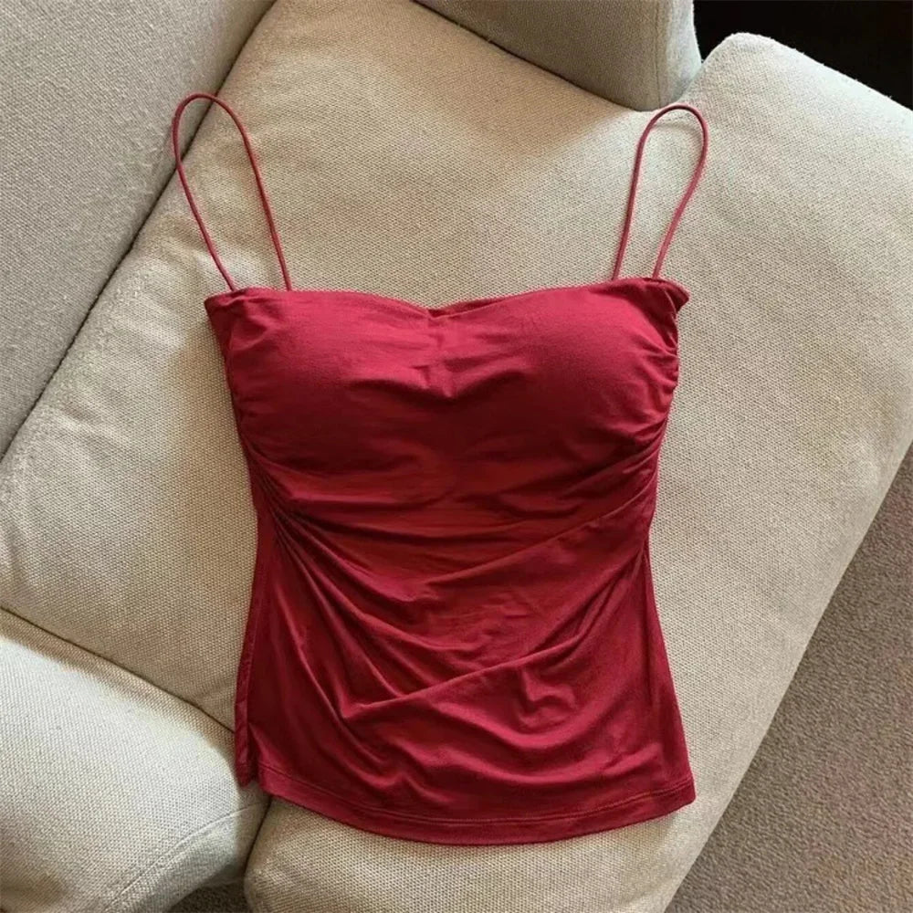 Red spaghetti strap top on a beige sofa. Corset taille cintrée élégant, sans manches avec pliage, coussinet poitrine, bretelles fines, top court solide, mode UK FTF Market.