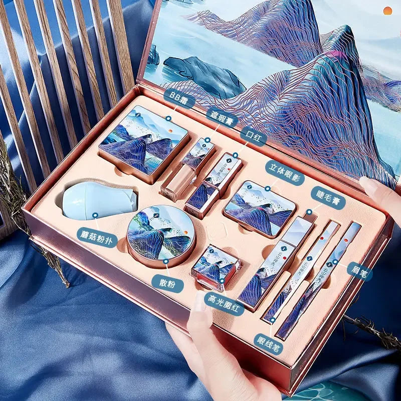 Makeup set with mountain-themed design in a decorative box held by a hand. Christmas makeup gift box with BB cream, lipstick, eyeshadow, eyebrow pencil, and brushes. Holiday beauty set for women & girls.