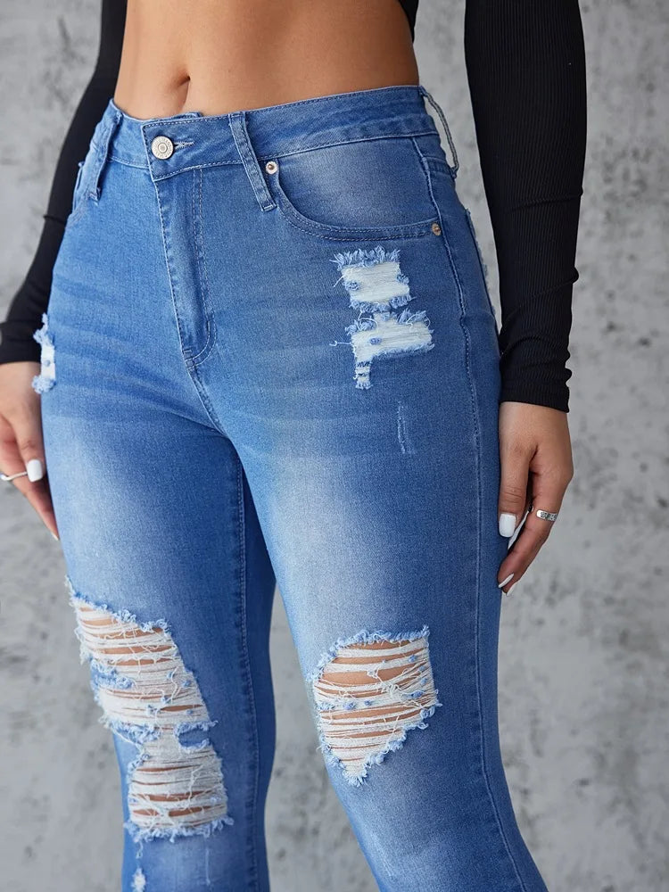 Blue distressed jeans worn by a person against a gray background. Women’s high waist ankle length skinny jeans, ripped and distressed, pockets, solid slim pencil fit. Vintage streetwear by ftf fashion UK.
