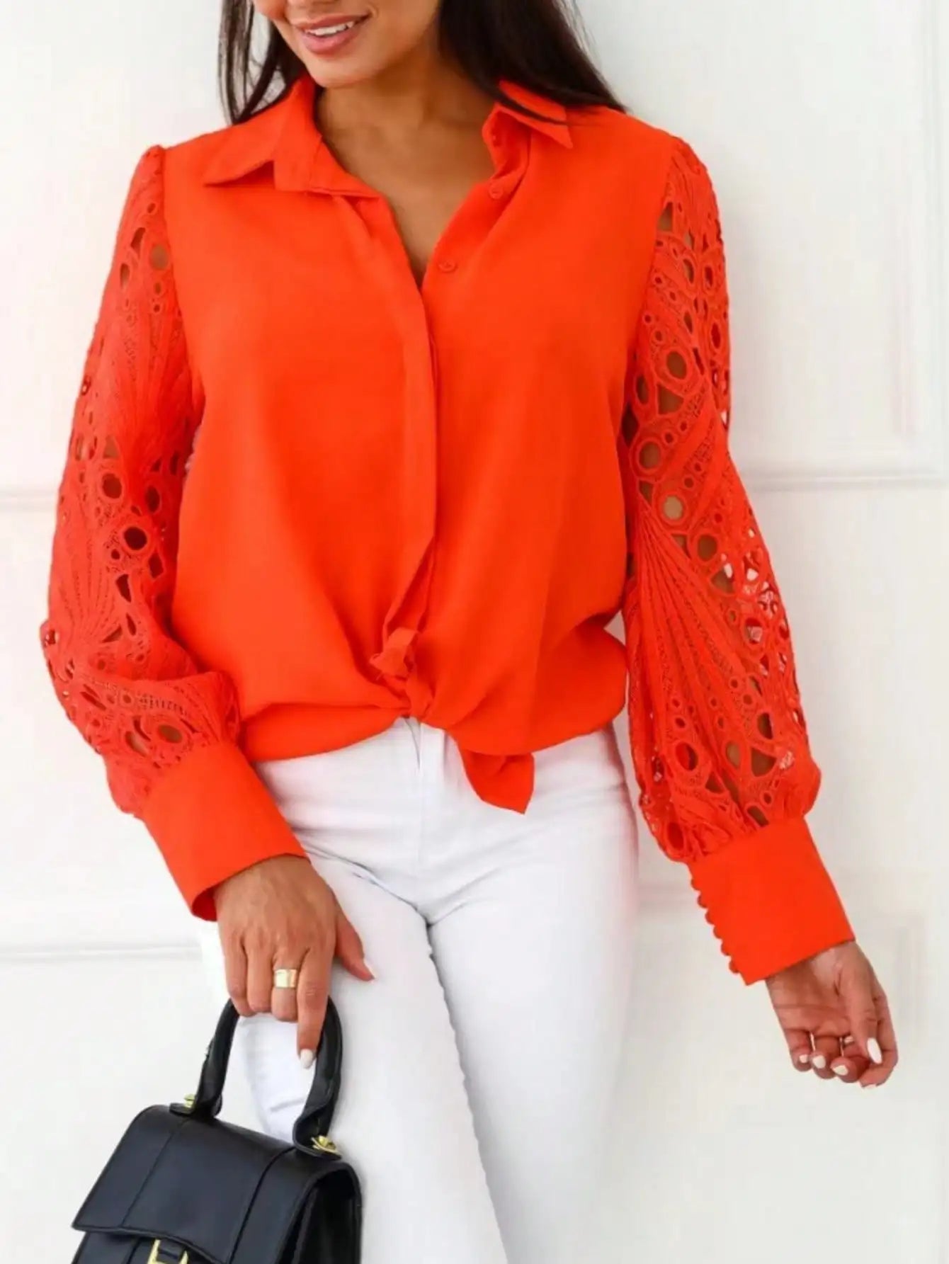Woman wearing a bright orange blouse with lace sleeves against a white background