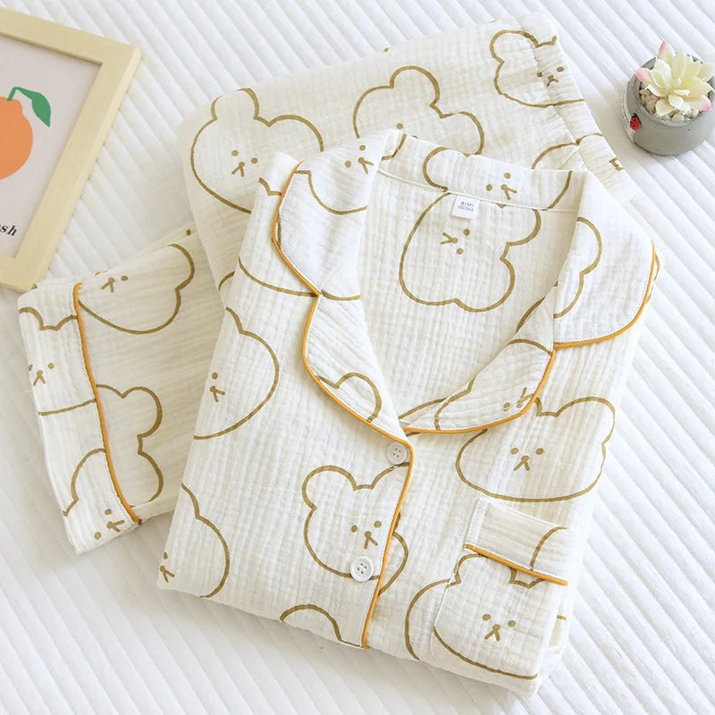 A floral print cotton pajama set in beige with yellow trim, consisting of a long-sleeved top and pants, laid flat on a white surface. Floral print cotton pajama set for women. Long sleeves, ankle-length pants, comfy fit, spring & autumn loungewear. Available UK—multiple colors.