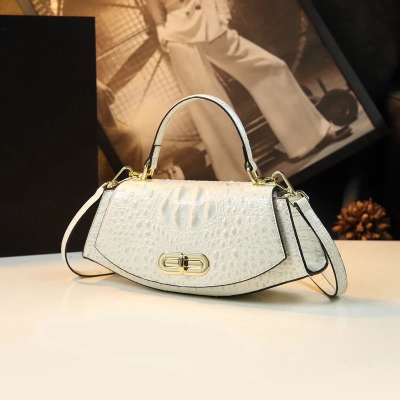 White handbag with gold accents on a light surface, blurred background