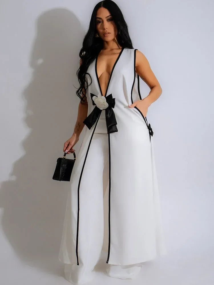 Woman wearing a white outfit with black accents against a plain background. Chic black and white sleeveless matching set with wide-leg pants UK