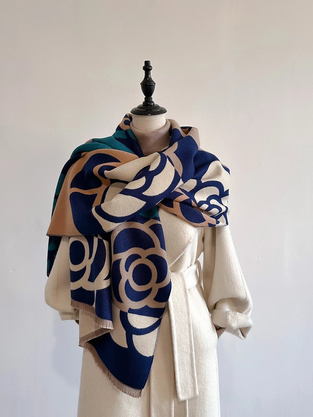 Mannequin wearing a patterned scarf and beige coat against a white background. Luxury cashmere-style floral scarf for women, extra-large and soft UK.