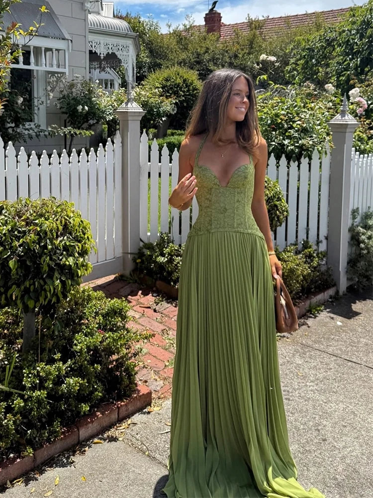 Woman in a green dress standing in a garden with a white picket fence.