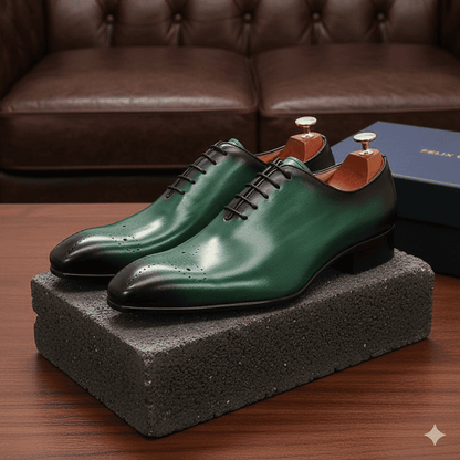 Green dress shoes on a gray block with a brown leather couch in the background