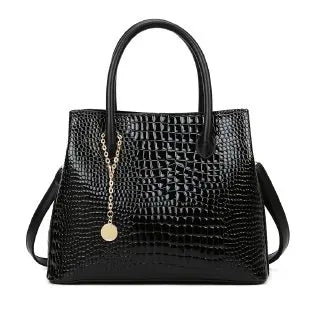 Black crocodile-patterned handbag with a gold zipper on a white background. Large capacity portable women’s crossbody bag with soft handle, zipper closure, chain accents, solid color print, perfect for daily fashion.