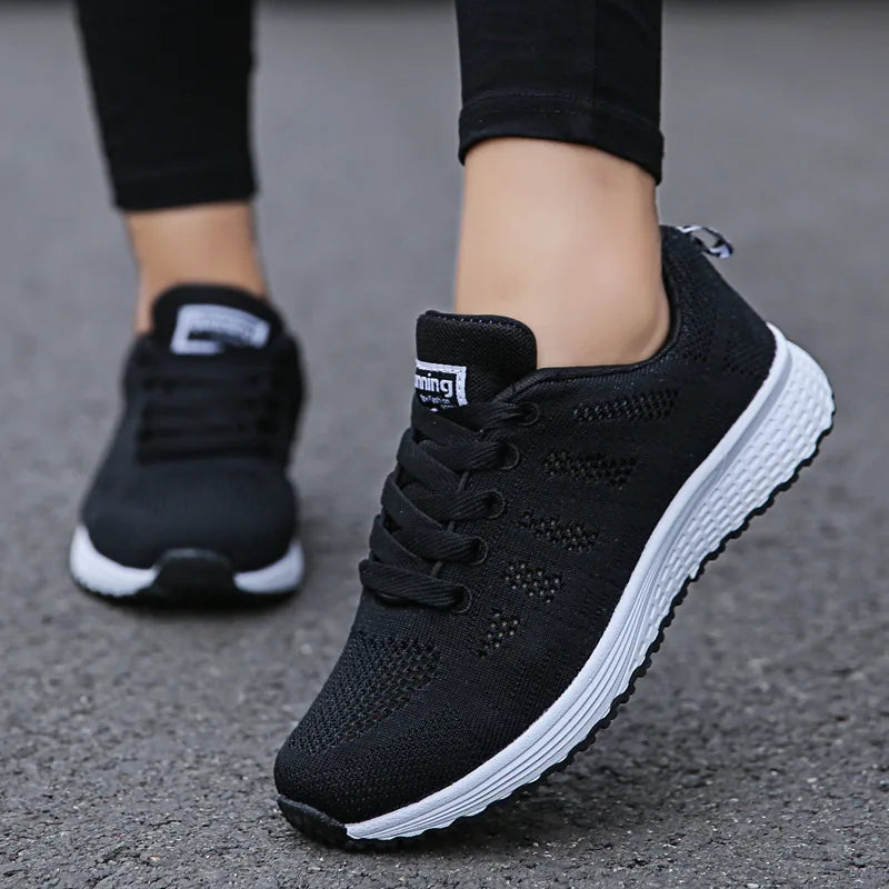 Black running shoes with white soles worn on a gray pavement