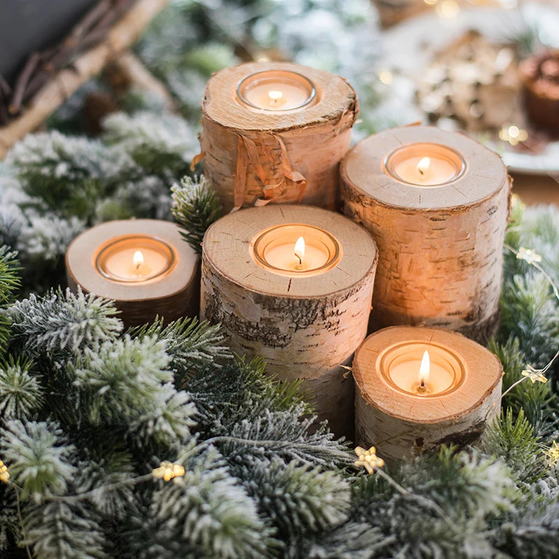Wooden candle holders with lit candles on a decorative background with greenery and lights.