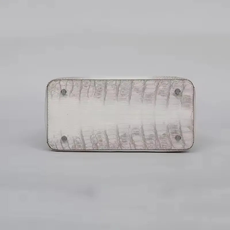 Rectangular clutch with textured surface and metallic accents on a light gray background. Genuine crocodile leather tote bag for women, waterproof pillow shape with zipper closure and removable strap. Luxury high-quality fashion accessory.