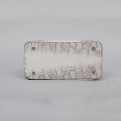 Rectangular clutch with textured surface and metallic accents on a light gray background. Genuine crocodile leather tote bag for women, waterproof pillow shape with zipper closure and removable strap. Luxury high-quality fashion accessory.