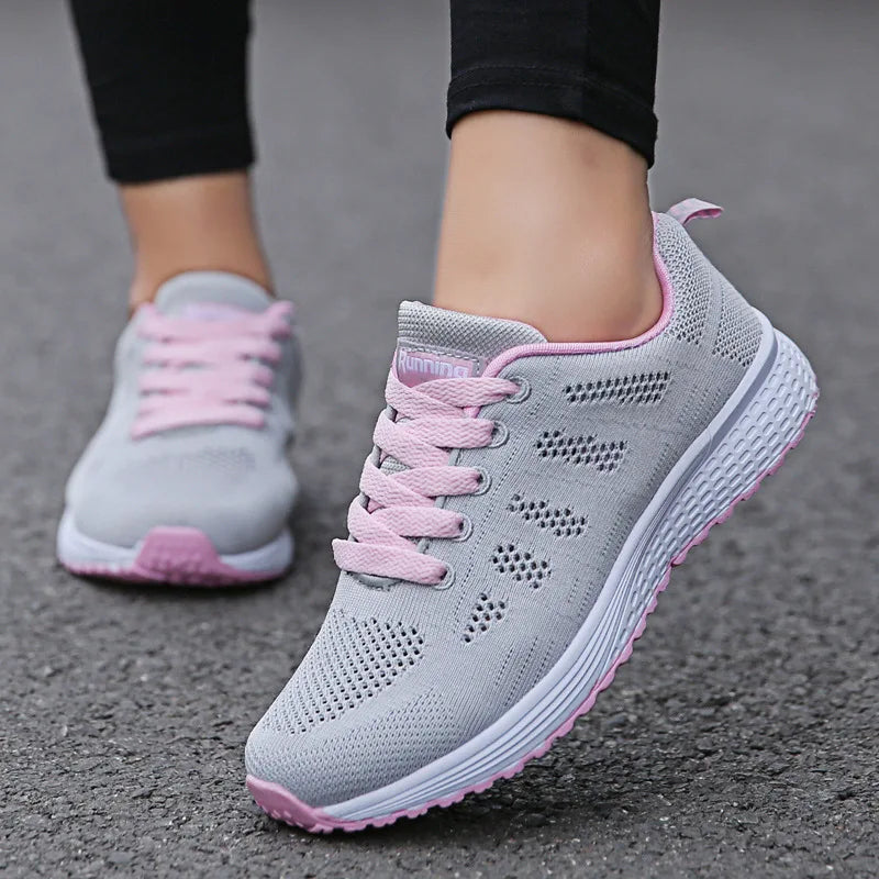 Gray sneakers with pink accents worn on a gray pavement surface