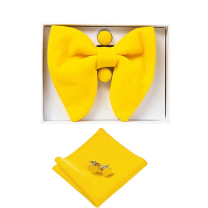 Yellow bow tie, pocket square, and cufflinks set in a box on a white background