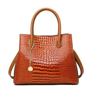 Brown crocodile-patterned handbag on a white background. Large capacity portable women’s crossbody bag with soft handle, zipper closure, chain accents, solid color print, perfect for daily fashion.