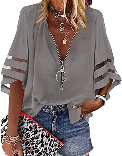Woman wearing a gray blouse with striped sleeves, denim shorts, and holding a leopard print clutch.