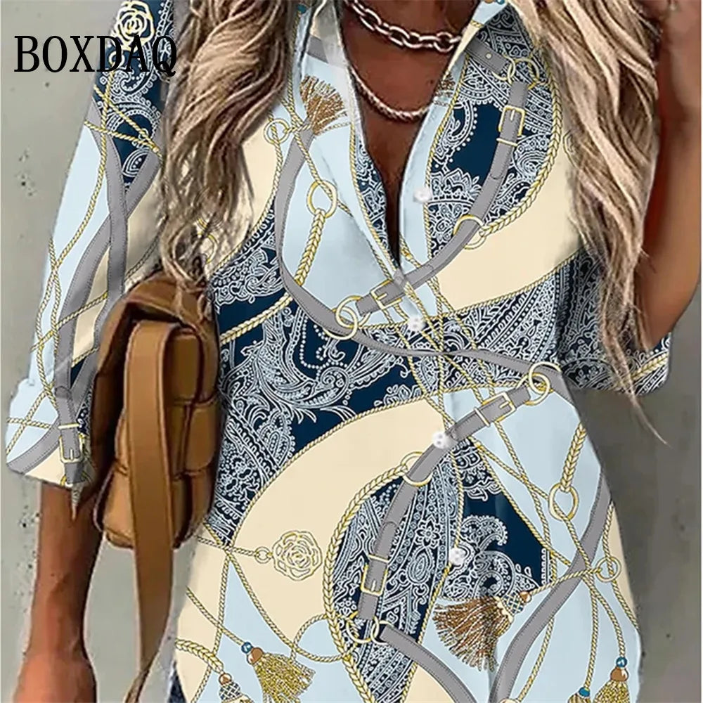 A woman wearing a short-sleeve button-up shirt dress with a luxury-inspired print featuring cream, navy blue, gray, and gold chain motifs. She is carrying a brown leather shoulder bag, and the brand name 'BOXBAO' is visible in the top left corner.