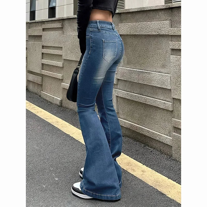 Person wearing blue flared jeans standing against a textured wall. Women’s high waist flared jeans, stretchy bootcut denim trousers. Thin fabric, solid color, bell bottoms style for casual chic UK fashion.