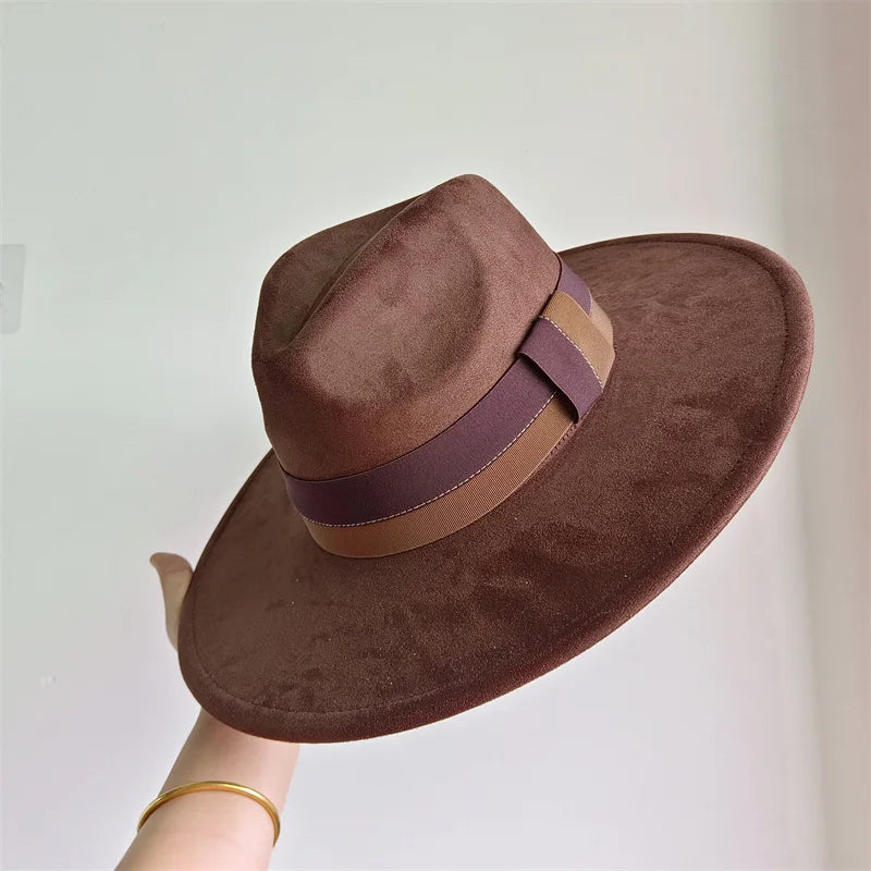 Brown fedora hat with a wide brim and brown band held by a hand against a light background