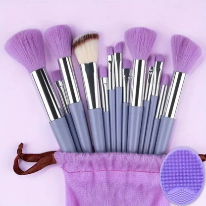Set of makeup brushes with purple bristles and gray handles, accompanied by a pink drawstring bag on a light purple background. Soft fluffy makeup brush set with wool fiber bristles and plastic handles. Complete set for powder, foundation, eyeshadow, and beauty blending.