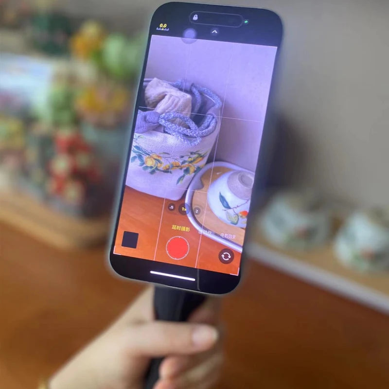 Phone screen showing a photo of a ceramic item with a blurred background. Magnetic phone tripod and wireless grip with remote control. Fits iPhone MagSafe and Samsung devices. Lightweight selfie stick tripod for creators.