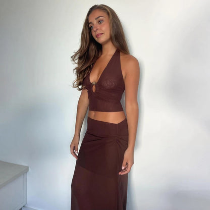 Woman wearing a brown dress against a white wall. Women’s 2-piece deep V swimsuit with long skirt, adjustable straps, solid color, beachwear, comfortable polyester/spandex fabric, flattering fit.