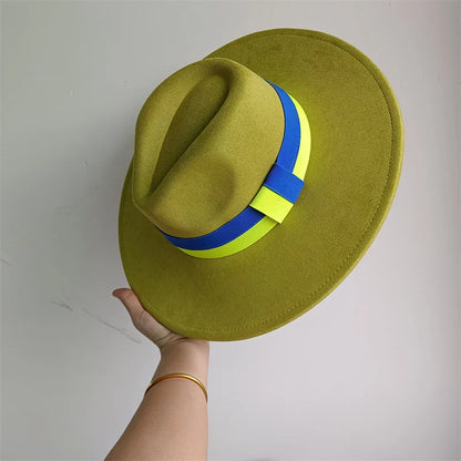 Green fedora hat with blue and yellow band held by a hand against a plain background