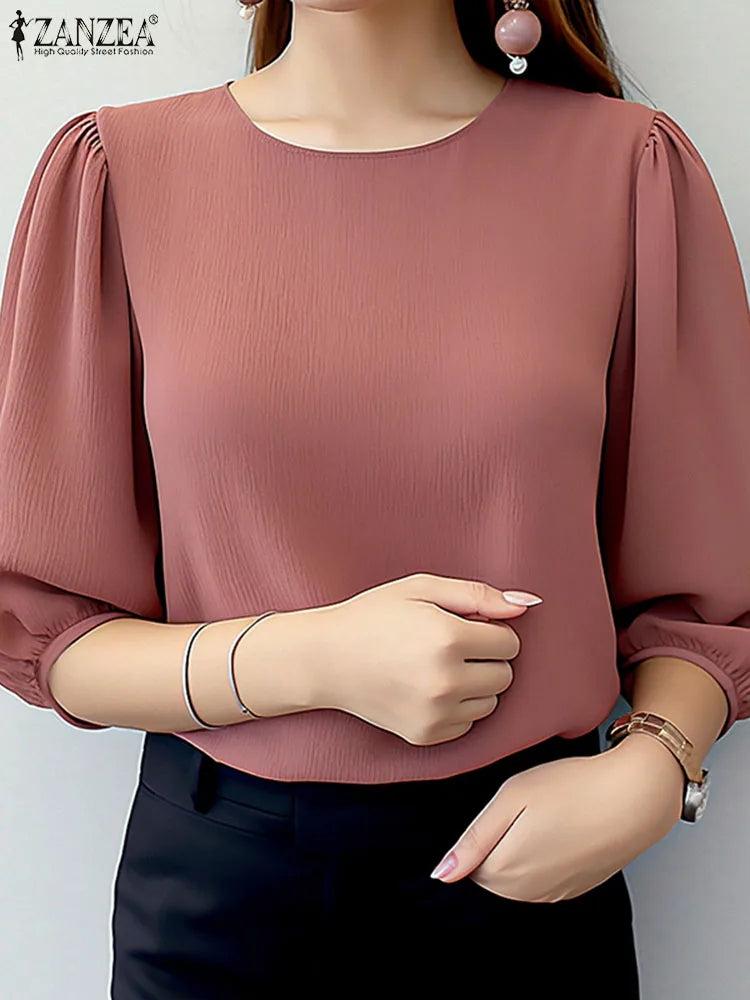 Person wearing a pink blouse with puffed sleeves on a plain background