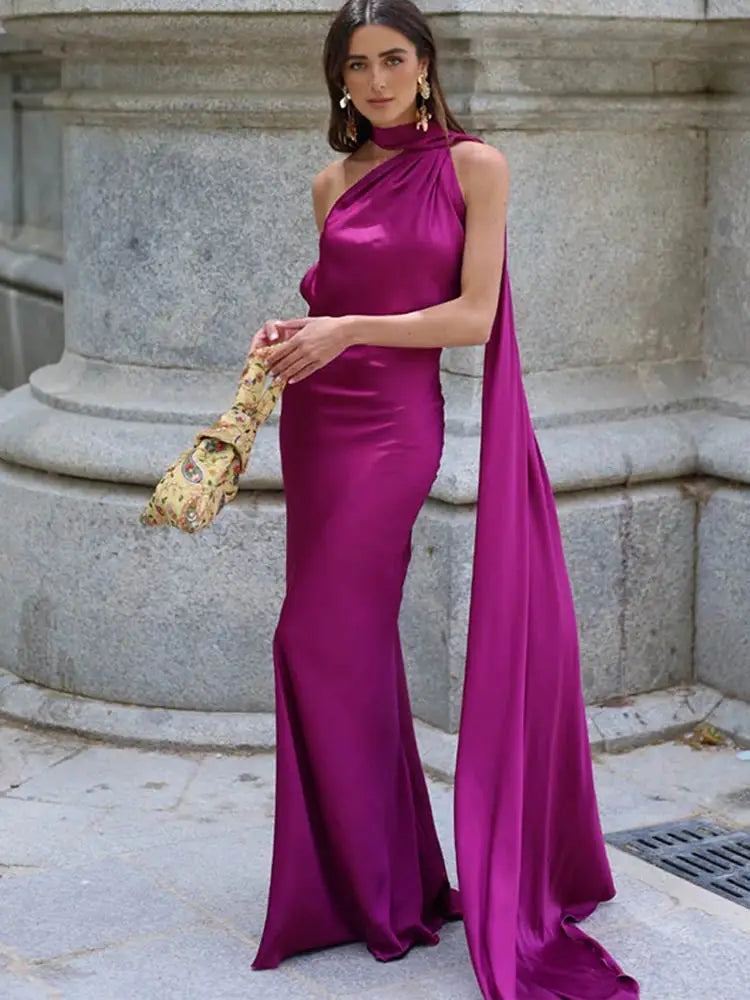 Woman in a magenta evening gown standing against a stone wall.