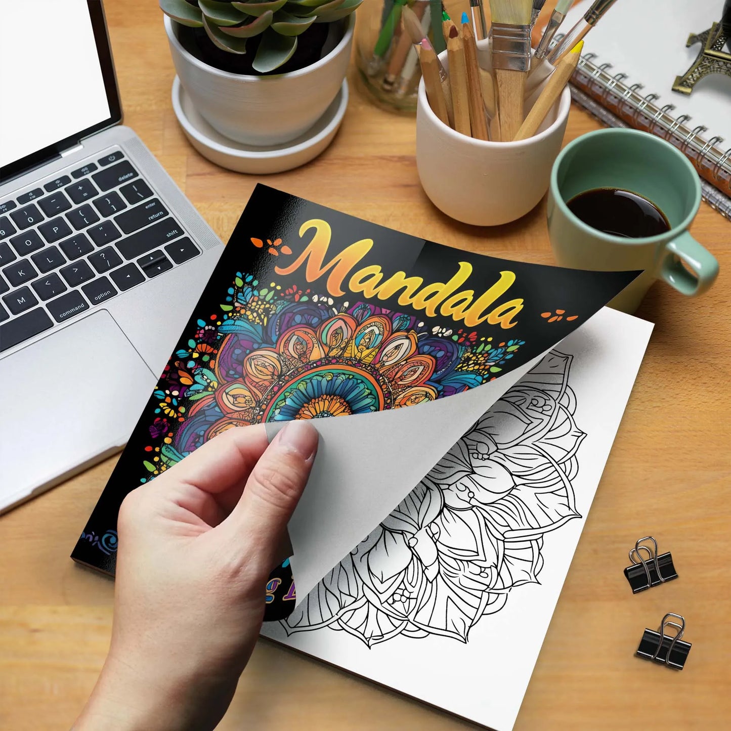 Coloring book with mandala design held over a coloring page on a desk with laptop, coffee, and stationery. Mandala coloring book for adults, stress relief, relaxation, creative color practice, perfect birthday party gift, UK FTF Market.