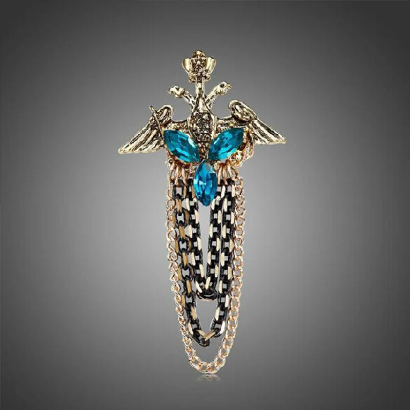 Decorative brooch with blue gemstones and gold chain on a gray background. Elegant rhinestone lapel pins for men and women. Tassel, crown, floral pins for suits, collars, weddings, parties. Zinc alloy metal, classic style.