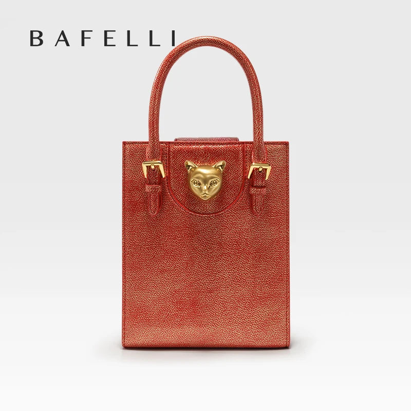 Red handbag with gold accents featuring a cat face emblem on a light gray background, branded 'Bafelli'. Unisex mini tote crossbody bag in split leather with flap pocket and lock closure. Hard box shape and polyester lining. Casual versatile style.
