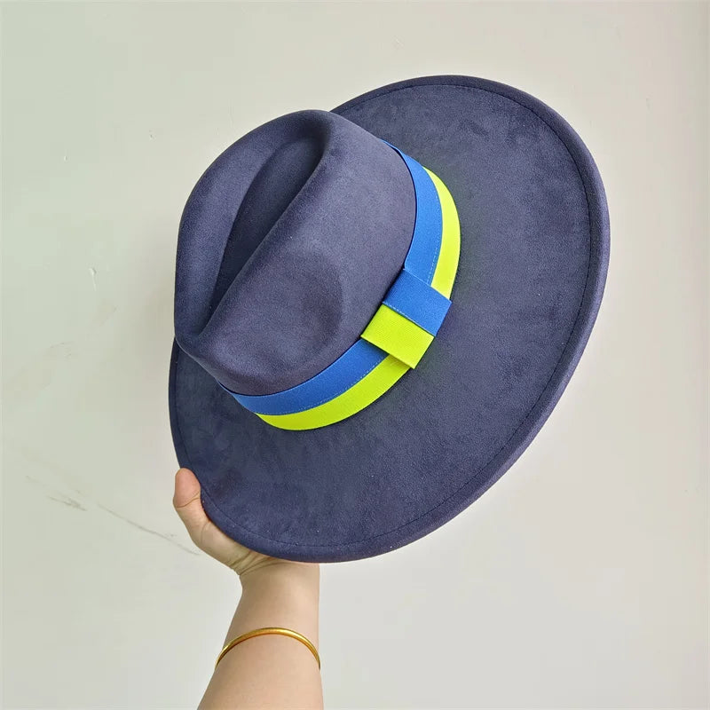 Blue hat with a blue and green band held by a hand against a light gray background