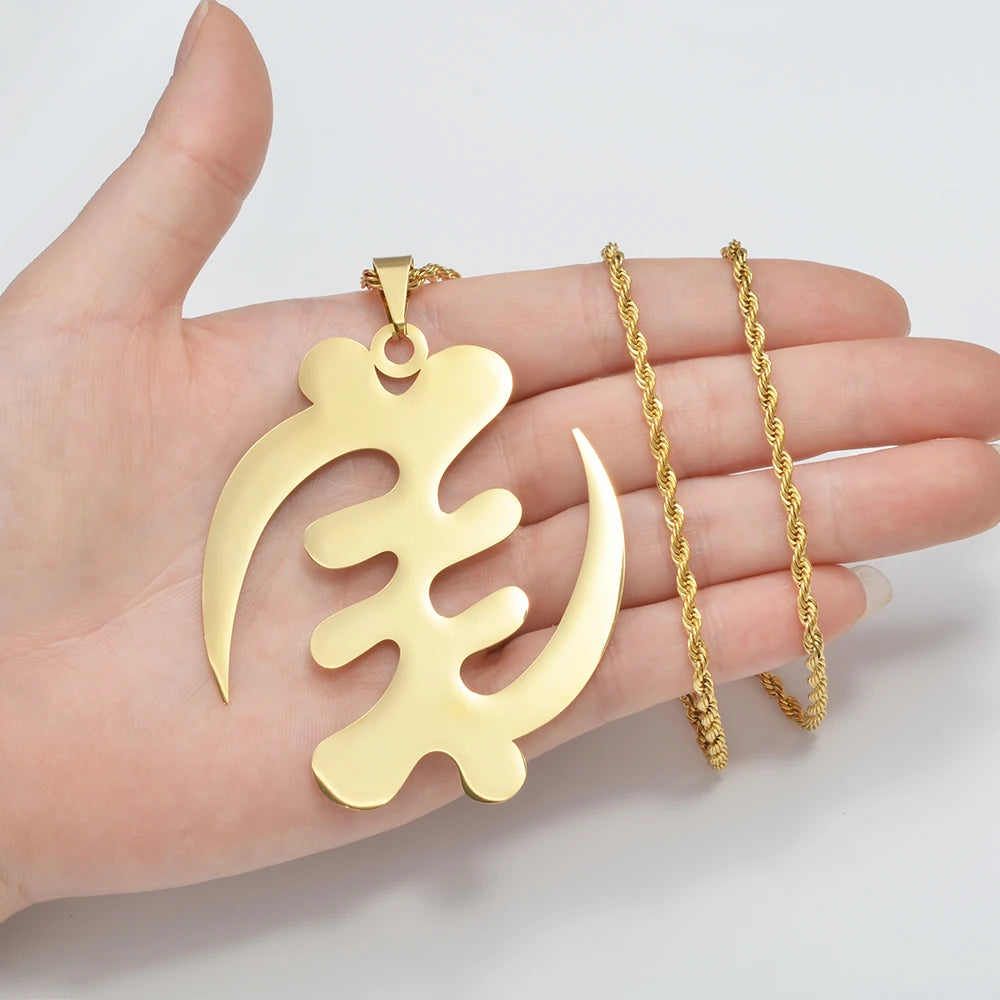 Gold pendant and chain held in a hand against a white background