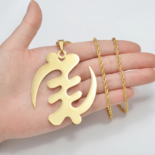 Gold pendant and chain held in a hand against a white background