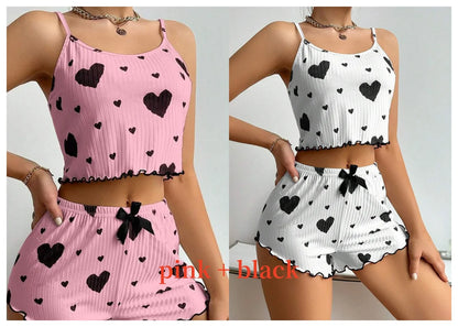 Two women wearing matching heart-patterned outfits in pink and white. Soft women’s pajama set, 2 pieces white tank top and shorts, breathable fabric with love print, comfortable casual sleepwear, UK FTF Market.