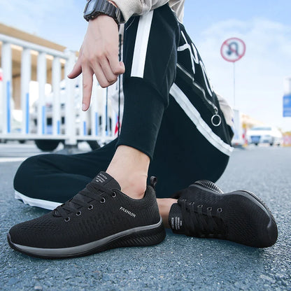 Person wearing black casual shoes with text on a road background. Men’s breathable running sneakers with mesh lining, PU insole, EVA outsole, lightweight casual sports shoes, perfect for jogging and walking.