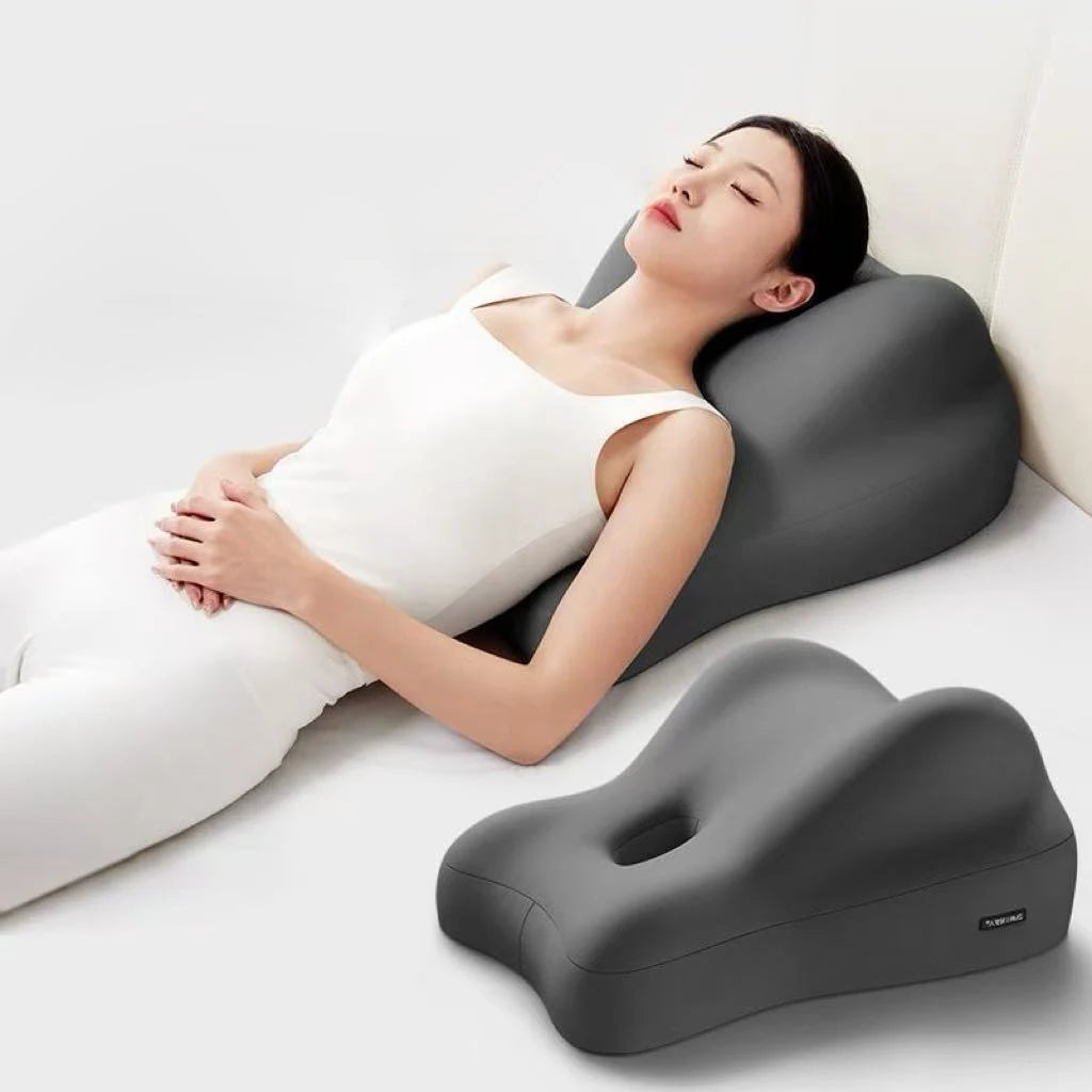 Woman lying on a wedge-shaped pillow with a plain background