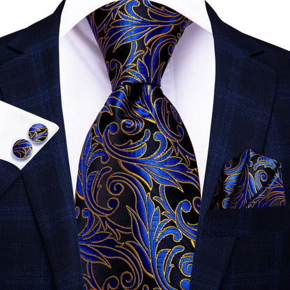 Navy suit with blue and gold paisley tie, pocket square, and cufflinks on a white background. Men’s luxury paisley silk tie and pocket square set, 8.5cm wide, for business or wedding. Red formal necktie, ftf fashion UK.