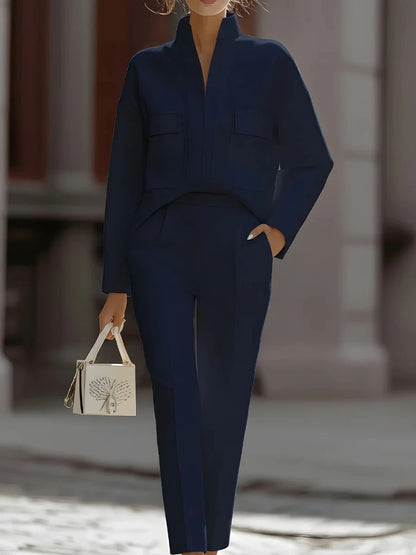 Person wearing a navy blue outfit holding a small handbag.