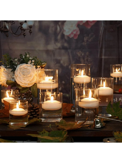 Candlelit scene with candles in glass holders on a wooden surface, surrounded by flowers and decorative elements.