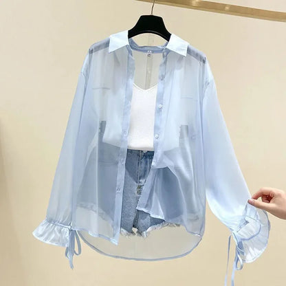 Light blue sheer blouse with white shirt and denim shorts on a beige background