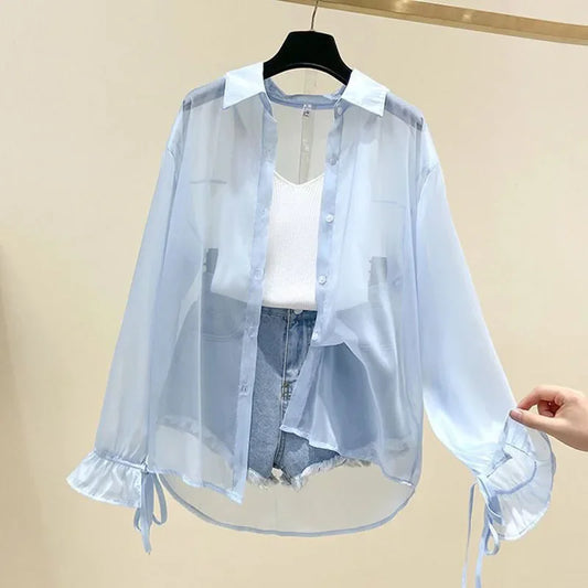 Light blue sheer blouse with white shirt and denim shorts on a beige background