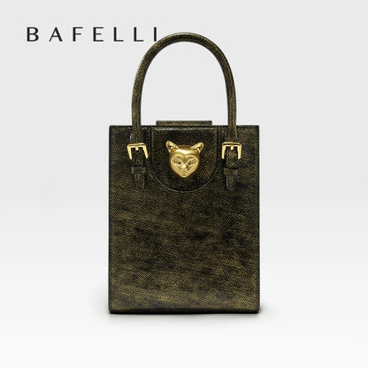 Gold handbag with a cat face emblem on a light gray background, featuring the brand 'Bafelli'. Unisex mini tote crossbody bag in split leather with flap pocket and lock closure. Hard box shape and polyester lining. Casual versatile style.