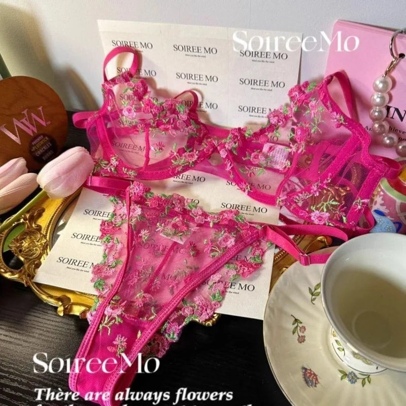 Pink floral lingerie set with 'SourceMo' branding on a table with a cup and saucer.