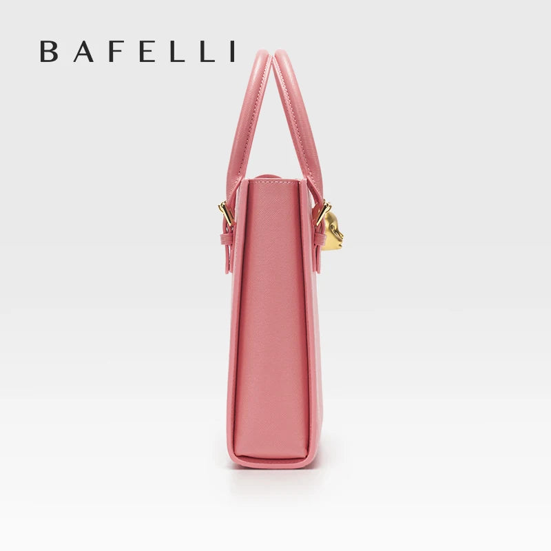 Pink handbag with gold accents on a white background, featuring the brand 'Bafelli'. Unisex mini tote crossbody bag in split leather with flap pocket and lock closure. Hard box shape and polyester lining. Casual versatile style.
