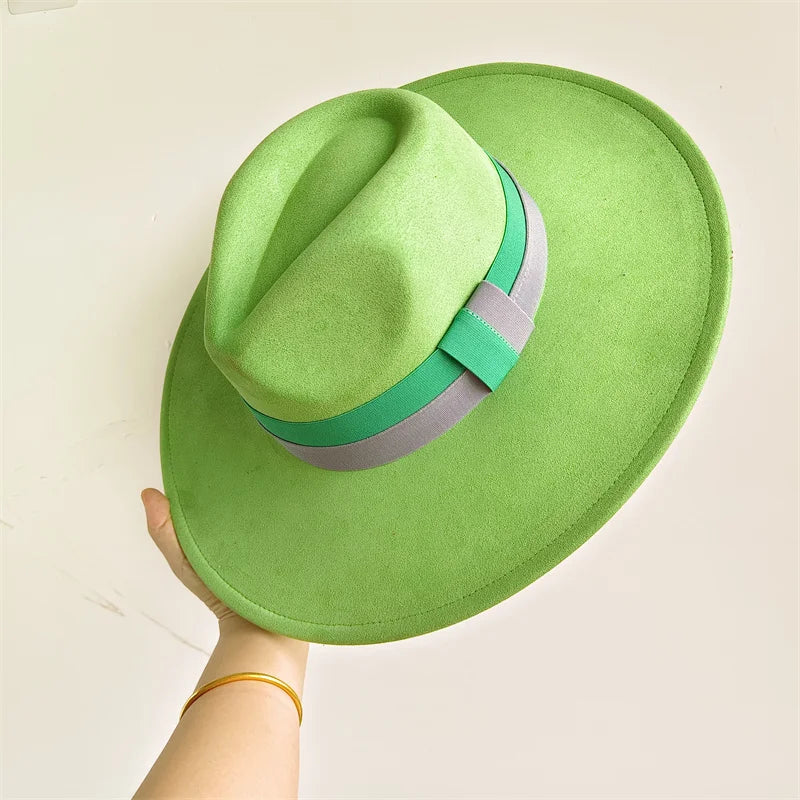 Green fedora hat with a band held by a hand against a light background