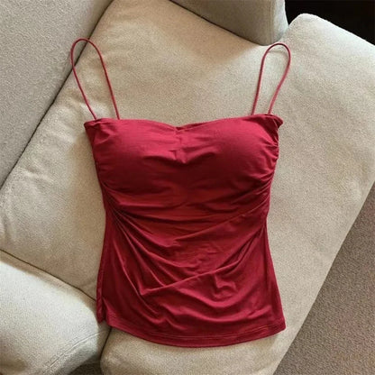 Red spaghetti strap top on a beige sofa. Corset taille cintrée élégant, sans manches avec pliage, coussinet poitrine, bretelles fines, top court solide, mode UK FTF Market.