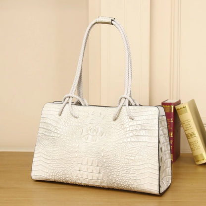 White textured handbag on a wooden surface with books in the background. Luxury women’s tote bag in genuine red crocodile leather. Large capacity, stylish handle, fashion travel handbag. Perfect for shoulder or portable use UK.