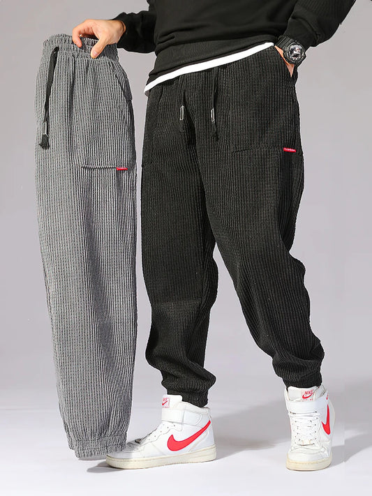 Two pairs of corduroy pants, one gray and one black, displayed side by side on a neutral background. Men's baggy corduroy jogger pants, tech fleece sweatpants, autumn winter harem trousers, elastic waist, thermal, UK FTF Market.